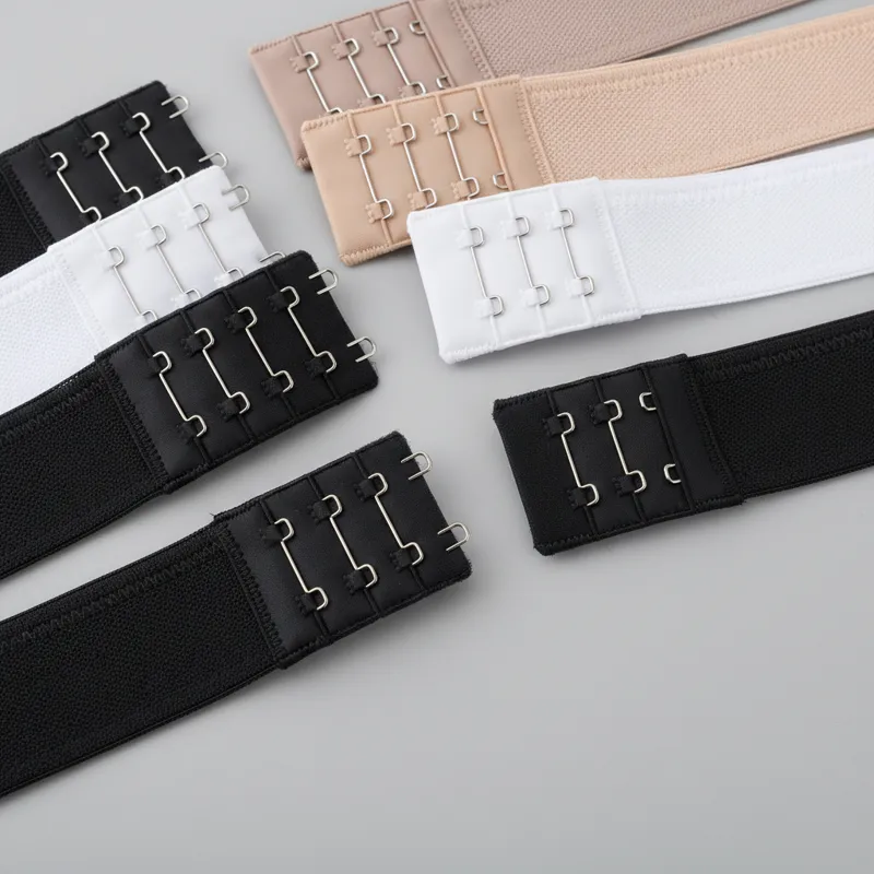 A close-up, well-lit shot of various bra extenders laid out on a clean, neutral background. Show a 2-hook, 3-hook, and 4-hook extender in different co