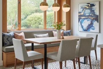 Modern built-in dining room bench with grey cushions and throw pillows, seamlessly integrated into a dining nook with a wooden table. The custom bench seating offers a space-saving solution for comfortable dining.