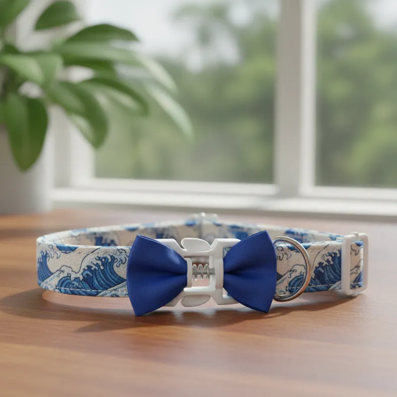 Close-up of a cat collar with a breakaway clasp clearly visible, demonstrating its safety mechanism. The collar has a small, simple bow tie attached.