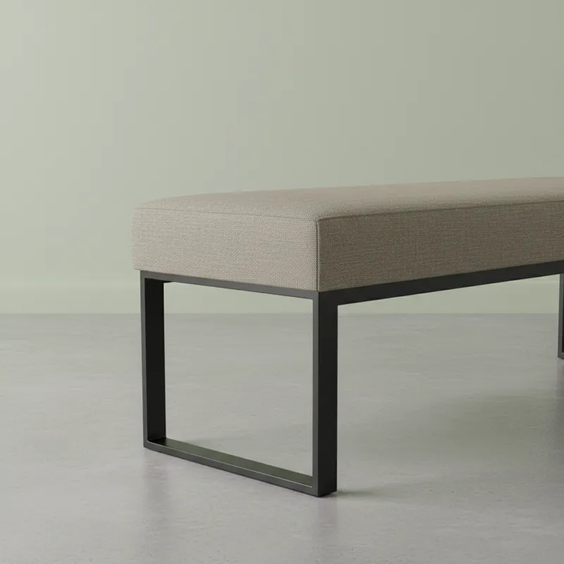 A close-up shot of a contemporary dining table bench showcasing clean lines, a subtle textured upholstery, and minimalist metal legs. The background i