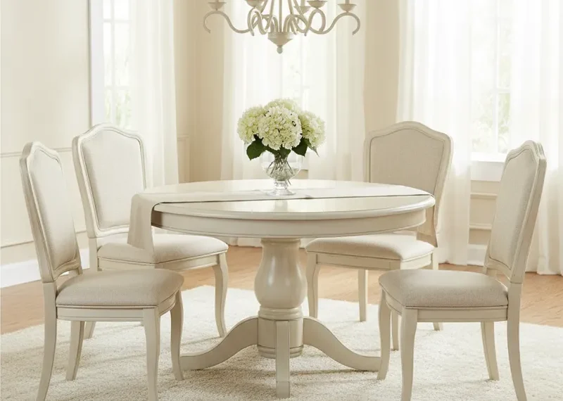 Modern cream round dining room table with four matching cream upholstered dining chairs set in a bright dining space.
