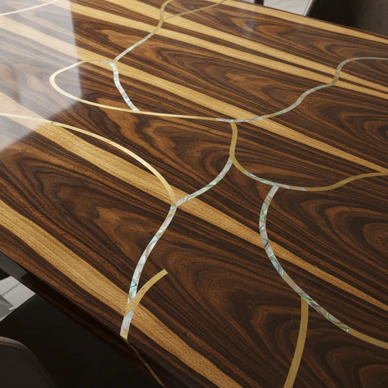 A close-up, high-detail shot showcasing the grain and finish of a luxurious dining table made from a rare hardwood like Macassar Ebony. The surface is
