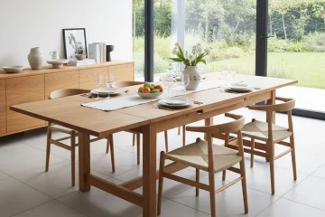 Modern extendable wooden dining table with six matching chairs, extended to accommodate more guests, set in a contemporary dining room.