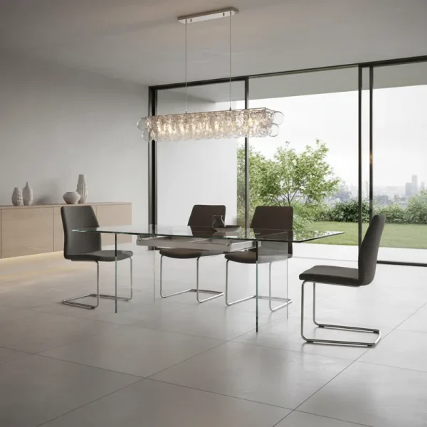 Modern extendable glass dining room table with a clear top and polished metal base, showcasing its sleek design and versatility for dining spaces.