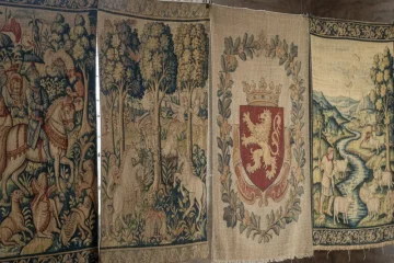 Close-up of a richly detailed vintage tapestry featuring a classic floral motif in muted tones, showcasing its intricate woven texture and antique quality.